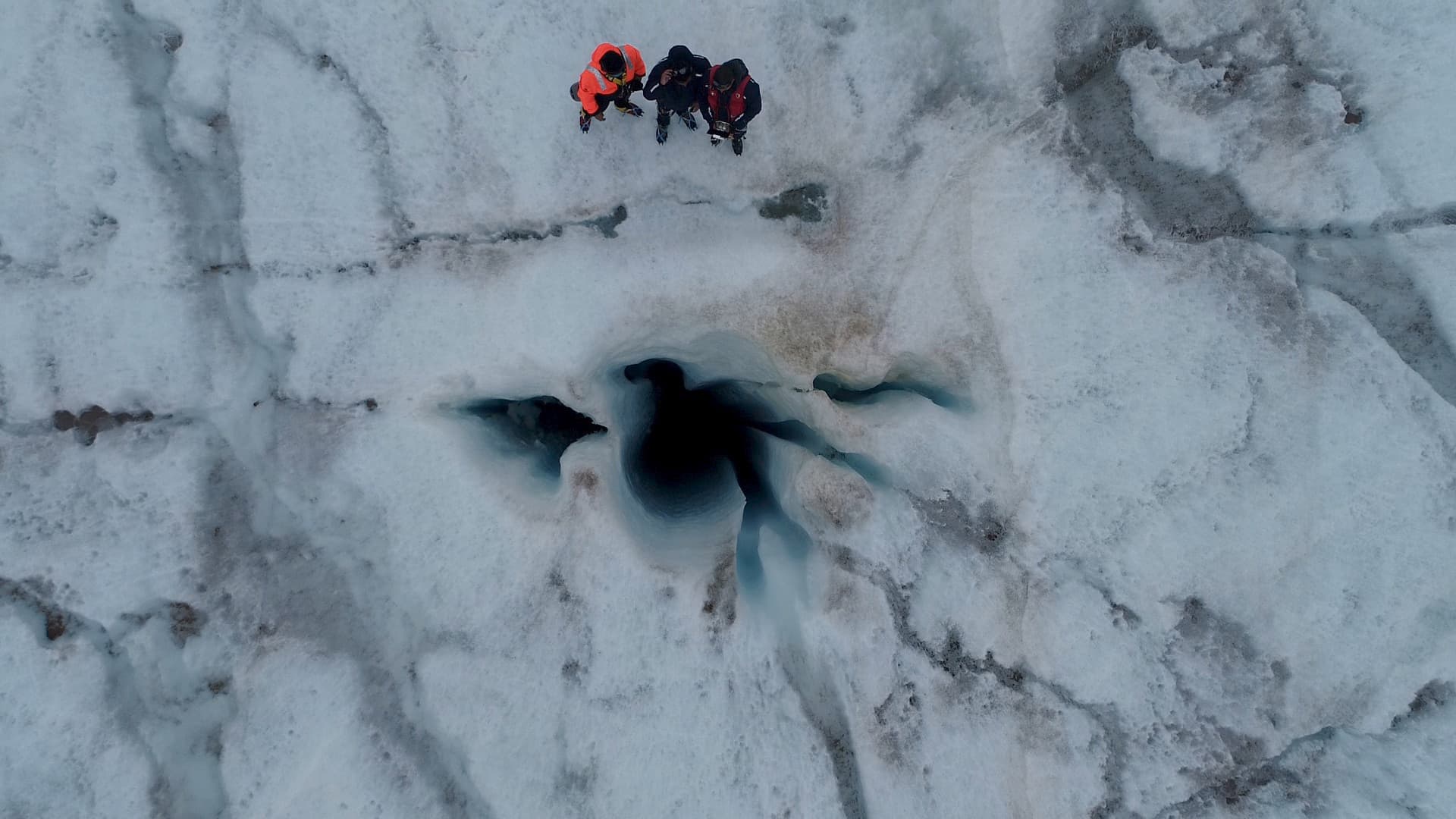 Team members beside a deep crevasse, giving scale to the survey on foot